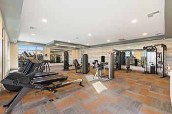 A gym with a variety of equipment including treadmills, weights, and exercise machines.